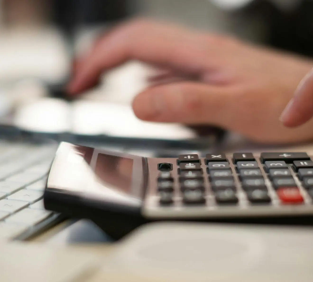Close-up of professional using calculator for financial data entry and accounting calculations