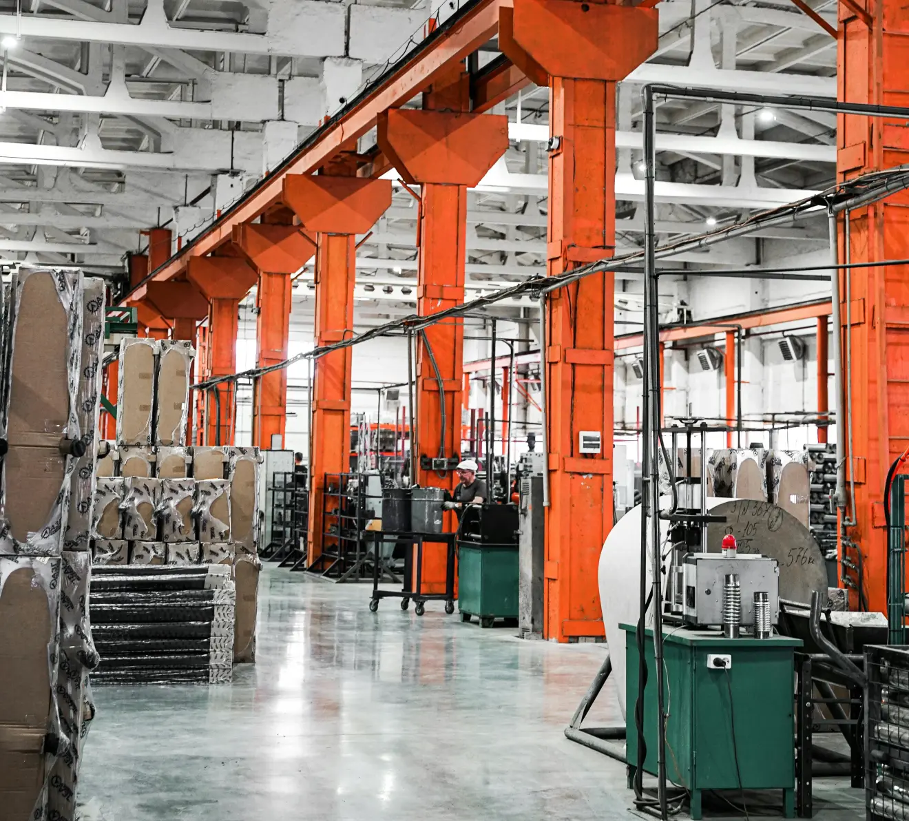 alt: Industrial manufacturing floor with production equipment and orange structural beams