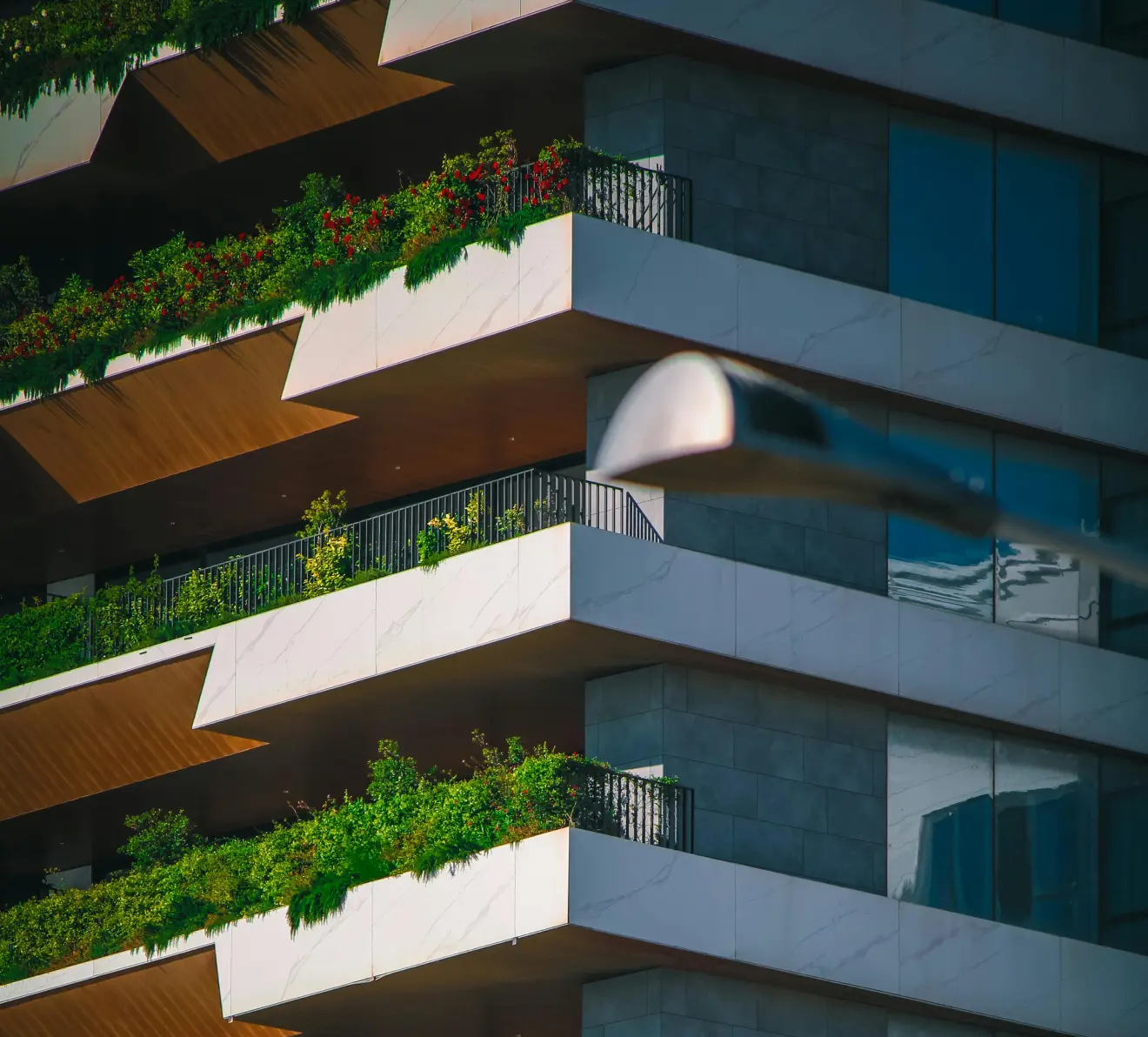 alt: Modern residential building with green balconies and sustainable real estate design